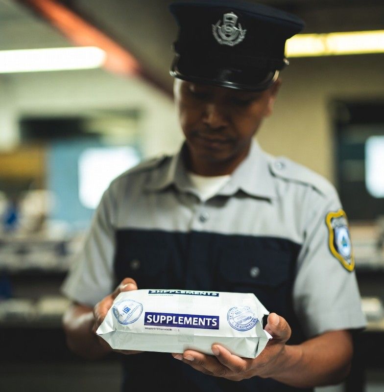 customs officer inspecting small international parcels labeled as supplements